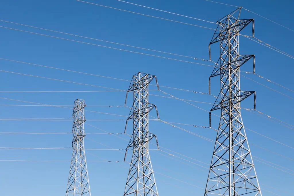 Transmission towers holding power lines, with a clear blue sky in the background